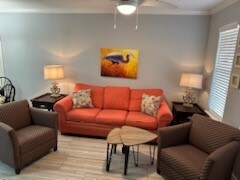 living room with ceiling fan, light wood-type flooring, and ornamental molding