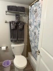 bathroom with toilet and shower / tub combo with curtain