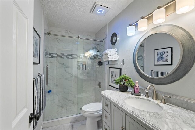 7425 Bourget Dr, Corpus Christi, TX 78413 - bathroom with a textured ceiling, a marble finish shower, vanity, toilet, and marble look tile flooring