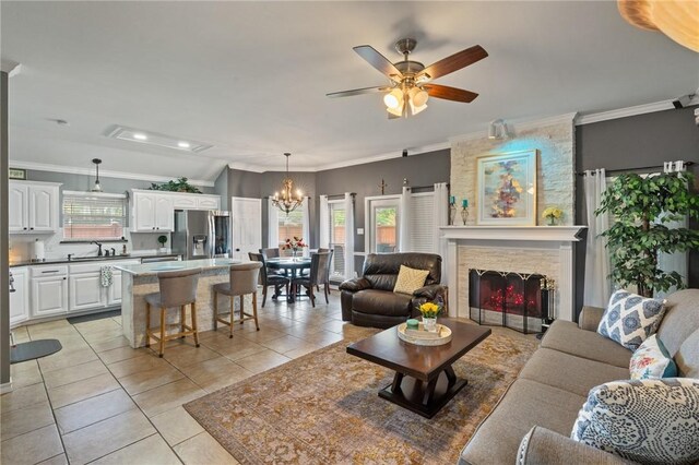 7425 Bourget Dr, Corpus Christi, TX 78413 - living room featuring light tile patterned floors, a chandelier, a ceiling fan, a fireplace, and ornamental molding