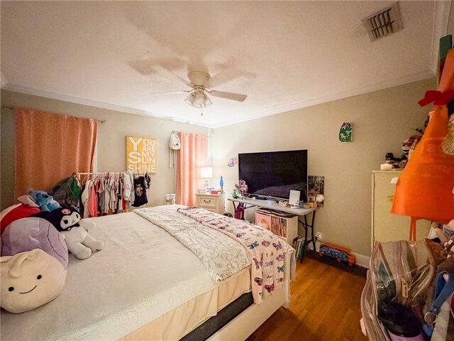 bedroom with ornamental molding, wood-type flooring, and ceiling fan