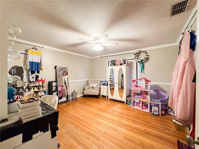 interior space featuring a textured ceiling, hardwood / wood-style flooring, crown molding, and ceiling fan