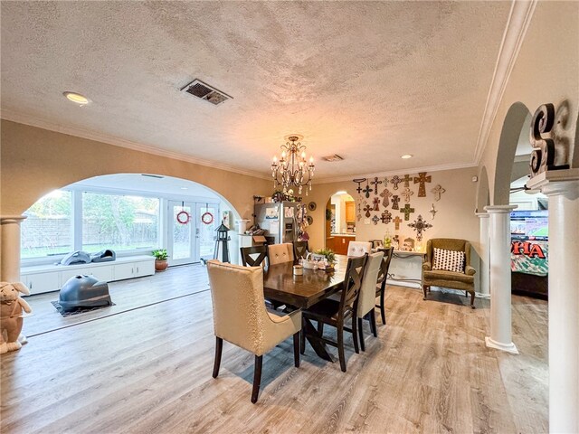 dining room featuring ornamental molding, an inviting chandelier, light hardwood / wood-style floors, and a textured ceiling