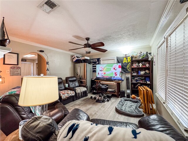 living room featuring ceiling fan, wood-type flooring, a textured ceiling, and crown molding