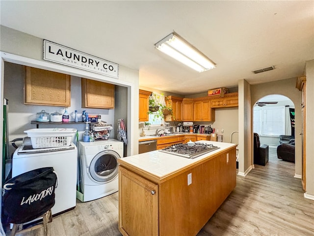 kitchen featuring separate washer and dryer, stainless steel appliances, tile counters, light hardwood / wood-style floors, and a center island