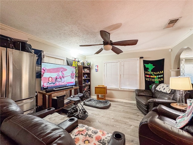 living room with a textured ceiling, hardwood / wood-style floors, ceiling fan, and crown molding