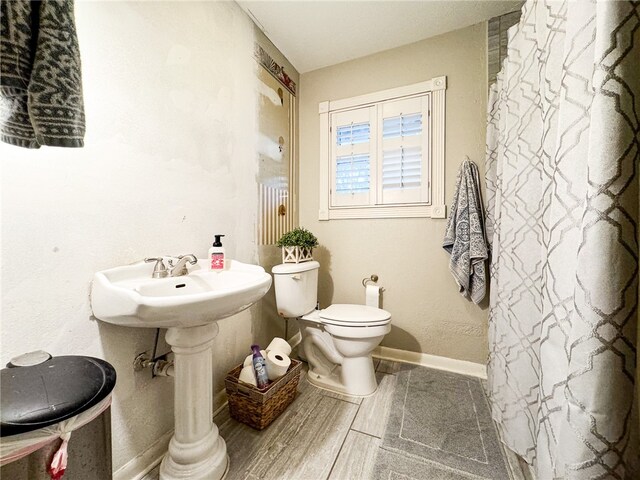 bathroom with toilet, a shower with curtain, and hardwood / wood-style flooring