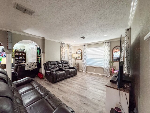 living room with a textured ceiling, wood-type flooring, and crown molding