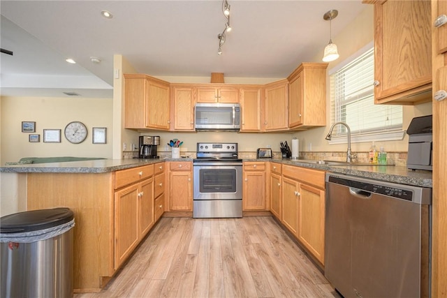 kitchen with sink, kitchen peninsula, light hardwood / wood-style floors, decorative light fixtures, and appliances with stainless steel finishes