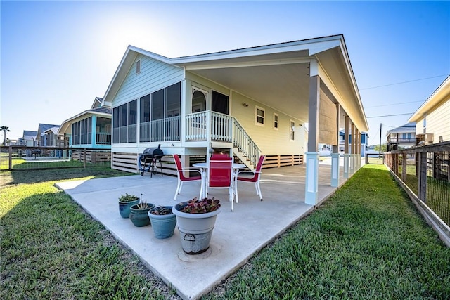 rear view of property featuring a patio area, a sunroom, and a yard