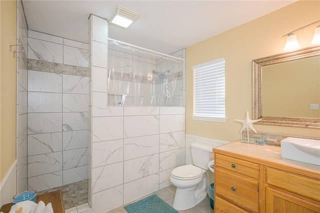 bathroom featuring a tile shower, tile patterned flooring, toilet, vanity, and tile walls