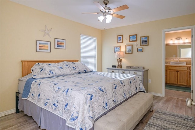 bedroom with connected bathroom, ceiling fan, light hardwood / wood-style flooring, and sink