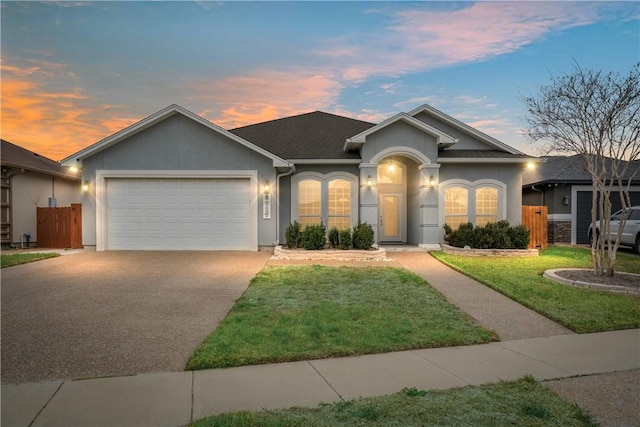 ranch-style home featuring an attached garage, fence, concrete driveway, stucco siding, and a front yard