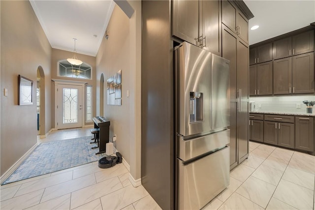 kitchen featuring arched walkways, light stone counters, hanging light fixtures, crown molding, and stainless steel refrigerator with ice dispenser