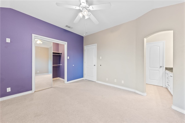 unfurnished bedroom with light colored carpet, lofted ceiling, ceiling fan, and a closet