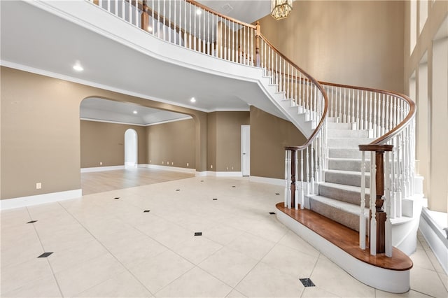 stairs with a high ceiling, a chandelier, and ornamental molding