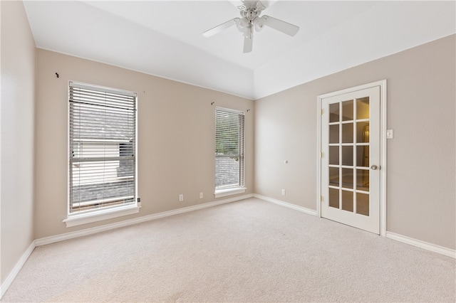 empty room featuring a wealth of natural light, light carpet, and ceiling fan