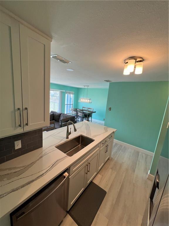 kitchen featuring backsplash, white cabinets, sink, light hardwood / wood-style flooring, and dishwasher