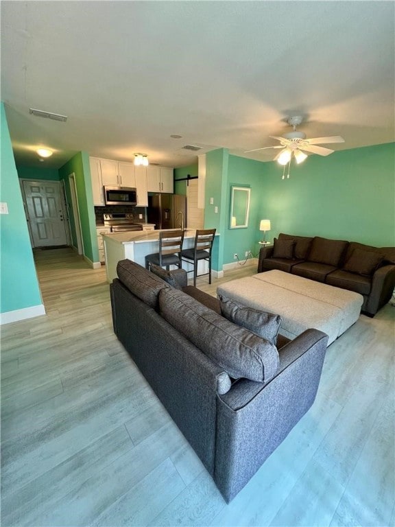 living room featuring ceiling fan and light hardwood / wood-style flooring