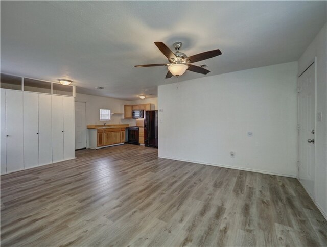 unfurnished living room with light hardwood / wood-style floors, ceiling fan, and sink