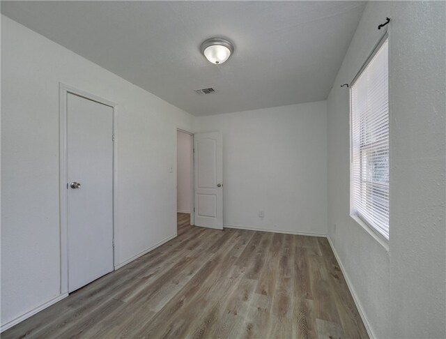 unfurnished bedroom with light hardwood / wood-style flooring and a closet