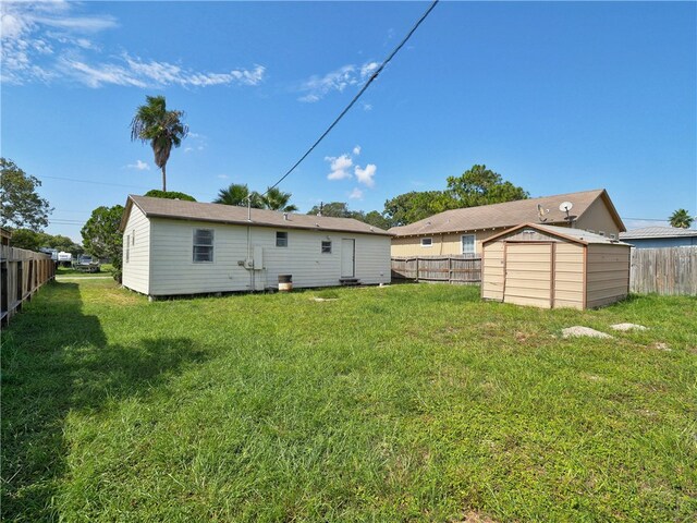 back of property with a storage unit and a yard