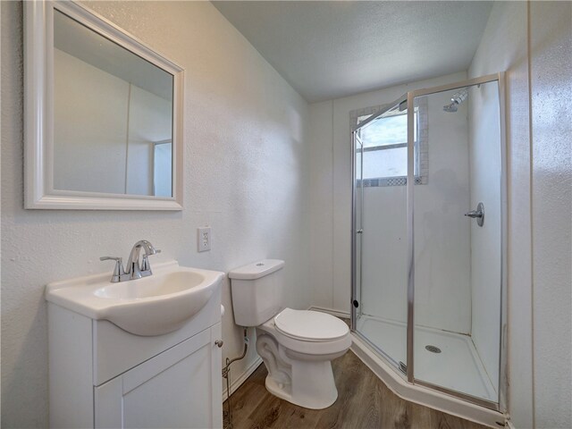 bathroom with toilet, a textured ceiling, hardwood / wood-style flooring, an enclosed shower, and vanity