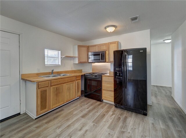 kitchen featuring black appliances, sink, and light hardwood / wood-style floors