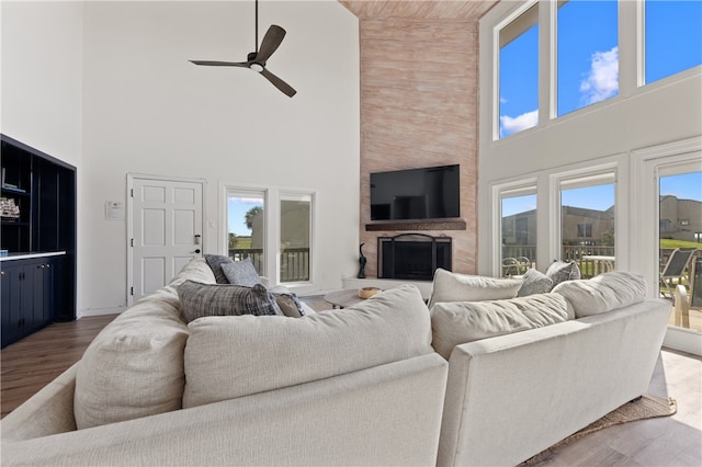 living room featuring high vaulted ceiling, a fireplace, wood-type flooring, and a healthy amount of sunlight