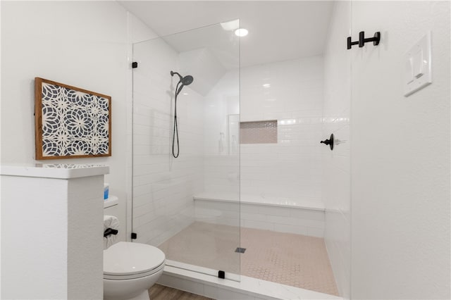 bathroom featuring hardwood / wood-style floors, tiled shower, and toilet