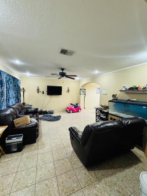 living room with a textured ceiling, ceiling fan, and light tile patterned floors