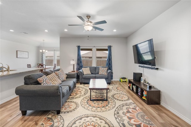 living area with ceiling fan with notable chandelier, recessed lighting, wood finished floors, and baseboards