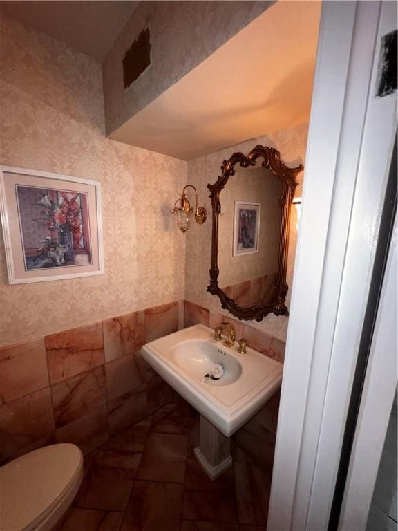 5445 Ocean Dr, Corpus Christi, TX 78412 - half bath with wallpapered walls, tile walls, and wainscoting
