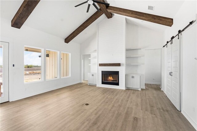 unfurnished living room with high vaulted ceiling, a large fireplace, and beam ceiling