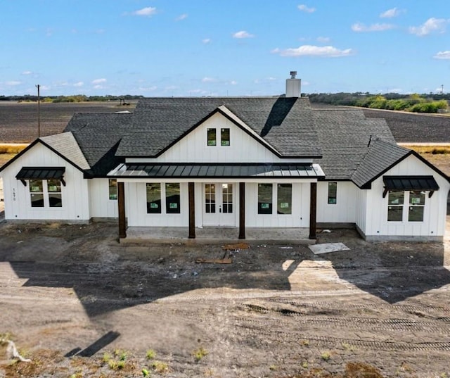 rear view of house with metal roof, roof with shingles, a standing seam roof, and board and batten siding