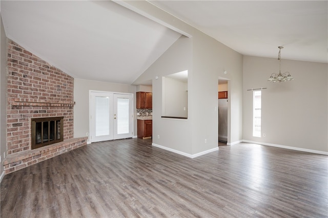 unfurnished living room with wood-type flooring, french doors, a fireplace, a notable chandelier, and high vaulted ceiling