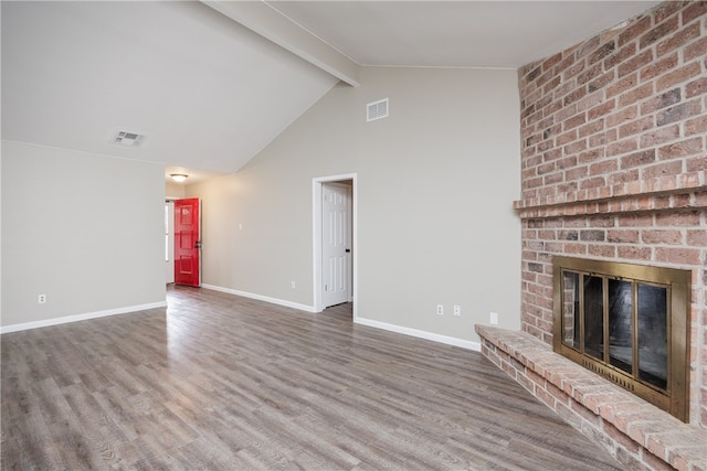 unfurnished living room with a fireplace, wood-type flooring, and lofted ceiling with beams