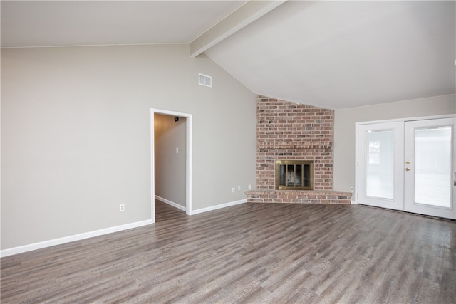 unfurnished living room with a brick fireplace, wood-type flooring, vaulted ceiling with beams, and french doors