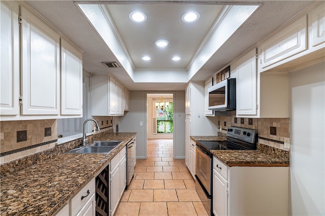 kitchen with stainless steel appliances, white cabinetry, sink, backsplash, and a tray ceiling