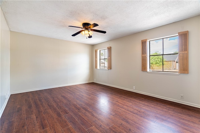 empty room with ceiling fan, a healthy amount of sunlight, a textured ceiling, and dark hardwood / wood-style flooring