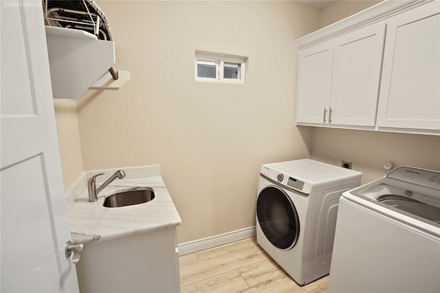 laundry room featuring light hardwood / wood-style floors, cabinets, sink, and washing machine and clothes dryer