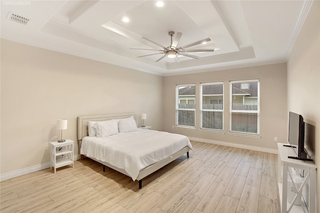 bedroom with ornamental molding, light hardwood / wood-style flooring, ceiling fan, and a raised ceiling