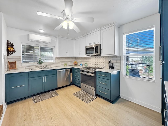 kitchen featuring stainless steel appliances, backsplash, light wood-style flooring, white cabinetry, and a wall mounted air conditioner