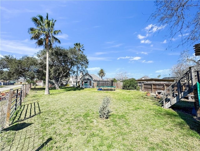 view of yard with a trampoline and fence