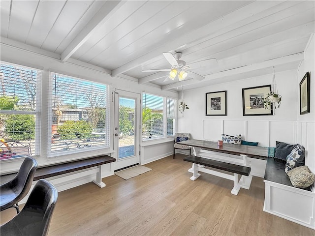 office space with beam ceiling, a decorative wall, light wood-style flooring, a ceiling fan, and wooden ceiling