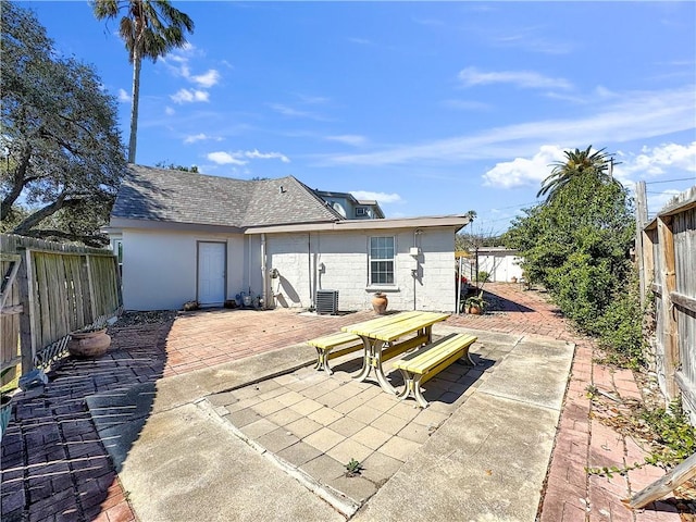 rear view of property with a patio, a shingled roof, a fenced backyard, and central air condition unit