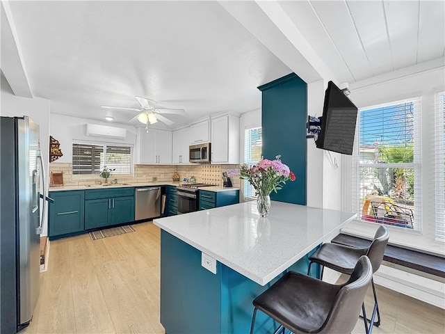 kitchen with appliances with stainless steel finishes, a kitchen breakfast bar, a peninsula, blue cabinetry, and a sink