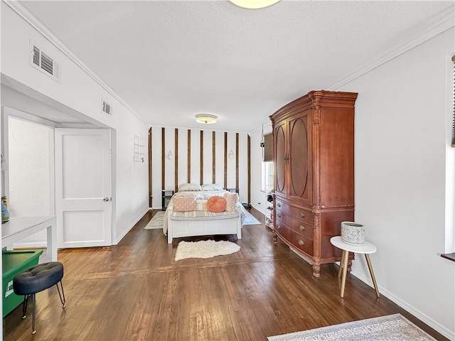 bedroom featuring visible vents, ornamental molding, a textured ceiling, wood finished floors, and baseboards