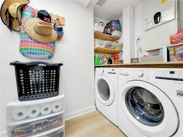 laundry room with laundry area, visible vents, baseboards, light wood finished floors, and washing machine and clothes dryer