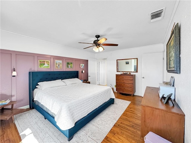 bedroom with ceiling fan, visible vents, and wood finished floors